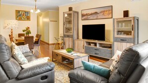 Een woonkamer met een bank, salontafel, tv-meubel en decoratieve accessoires.