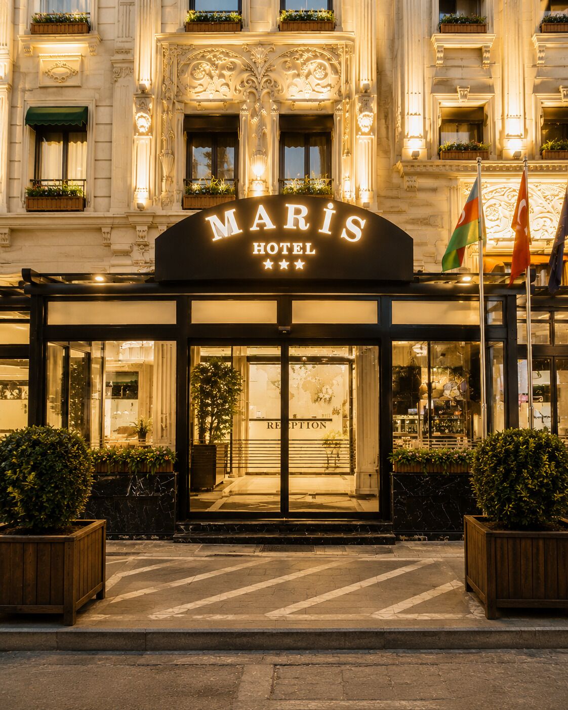 Entrada del Hotel Maris con área de recepción, ventanas amplias y banderas.