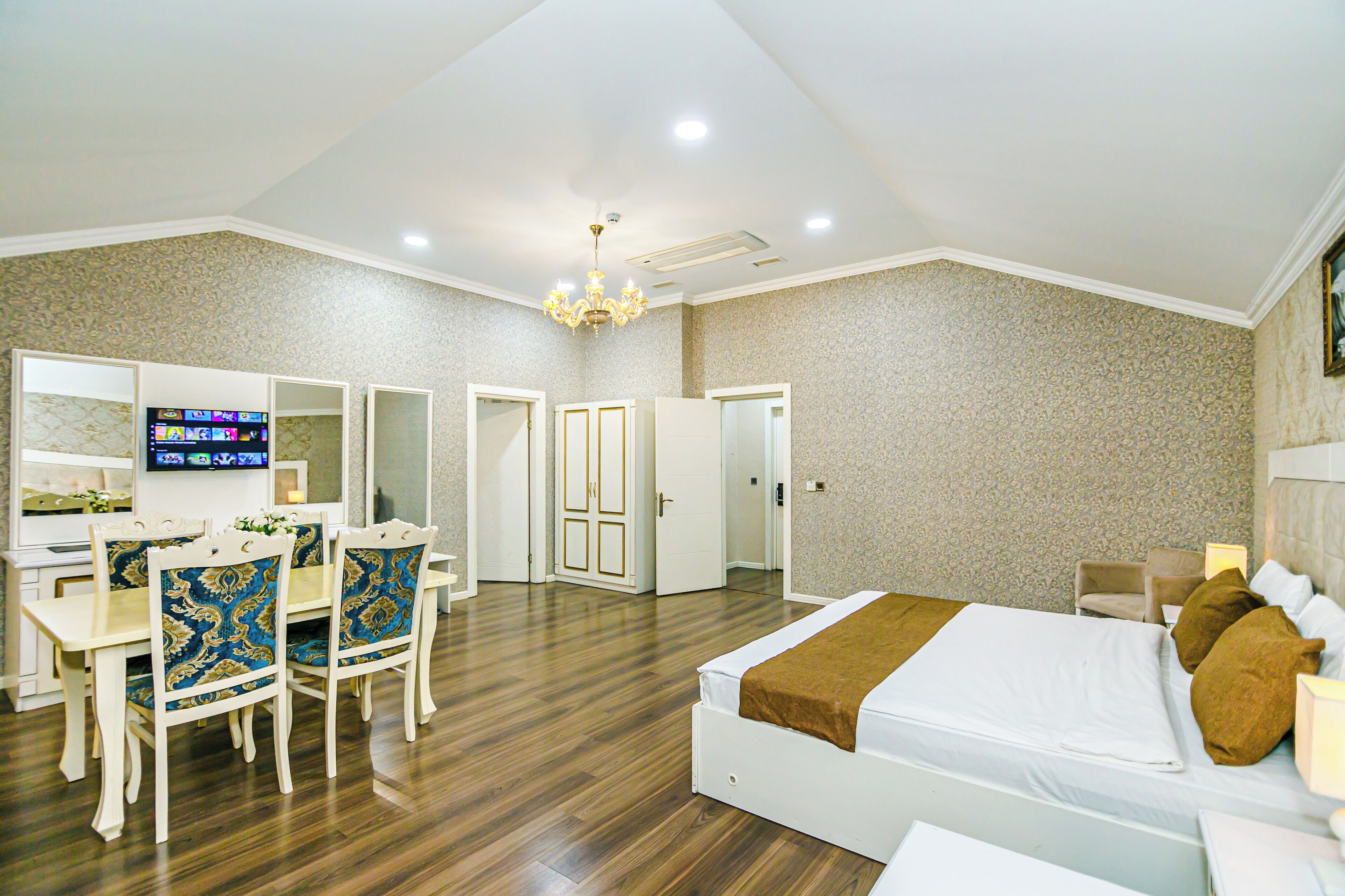 A hotel room with a bed, bedside table, lamp, and a TV on a stand.