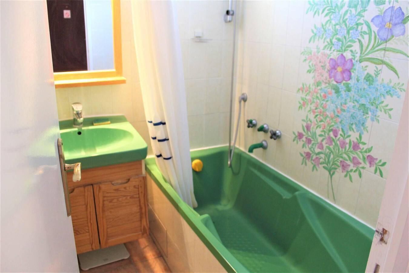 Une salle de bain avec une baignoire verte, un meuble en bois, un lavabo et une douche.