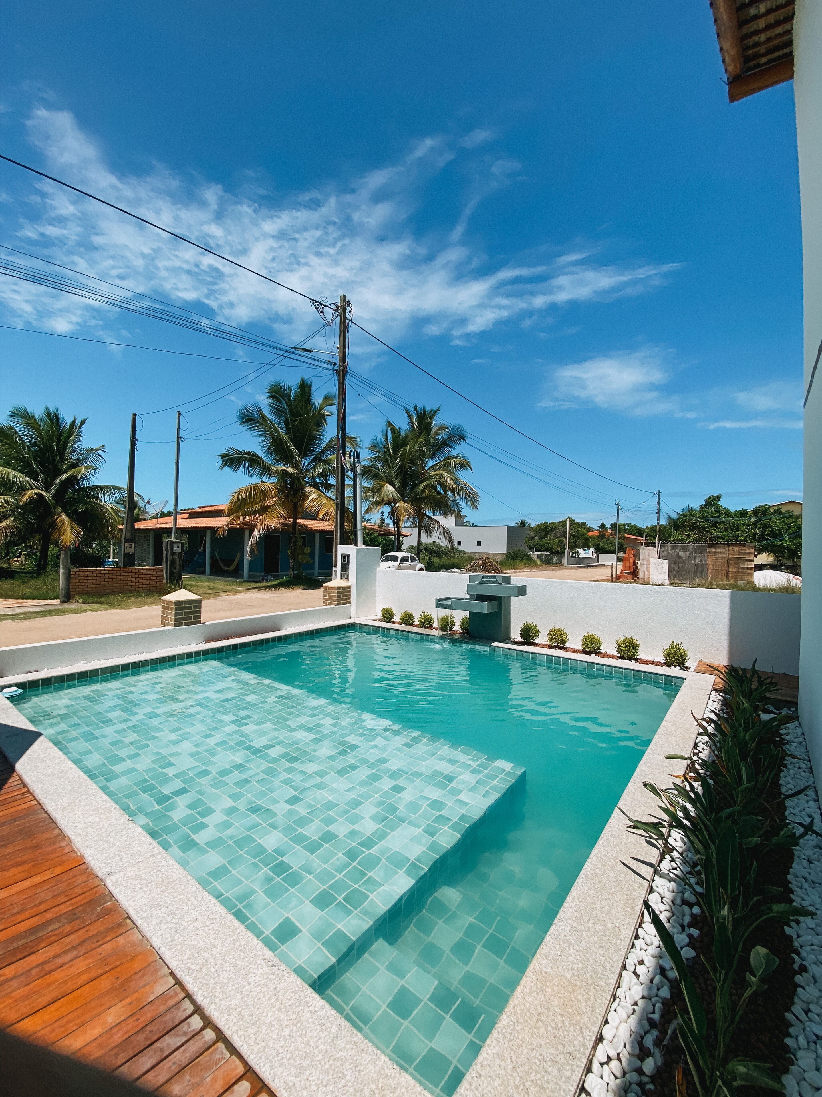 A rectangular swimming pool with a tiled edge, surrounded by a wooden deck and white pebbles.