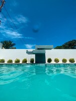 Una piscina al aire libre, sombrillas, sillones reclinables de piscina