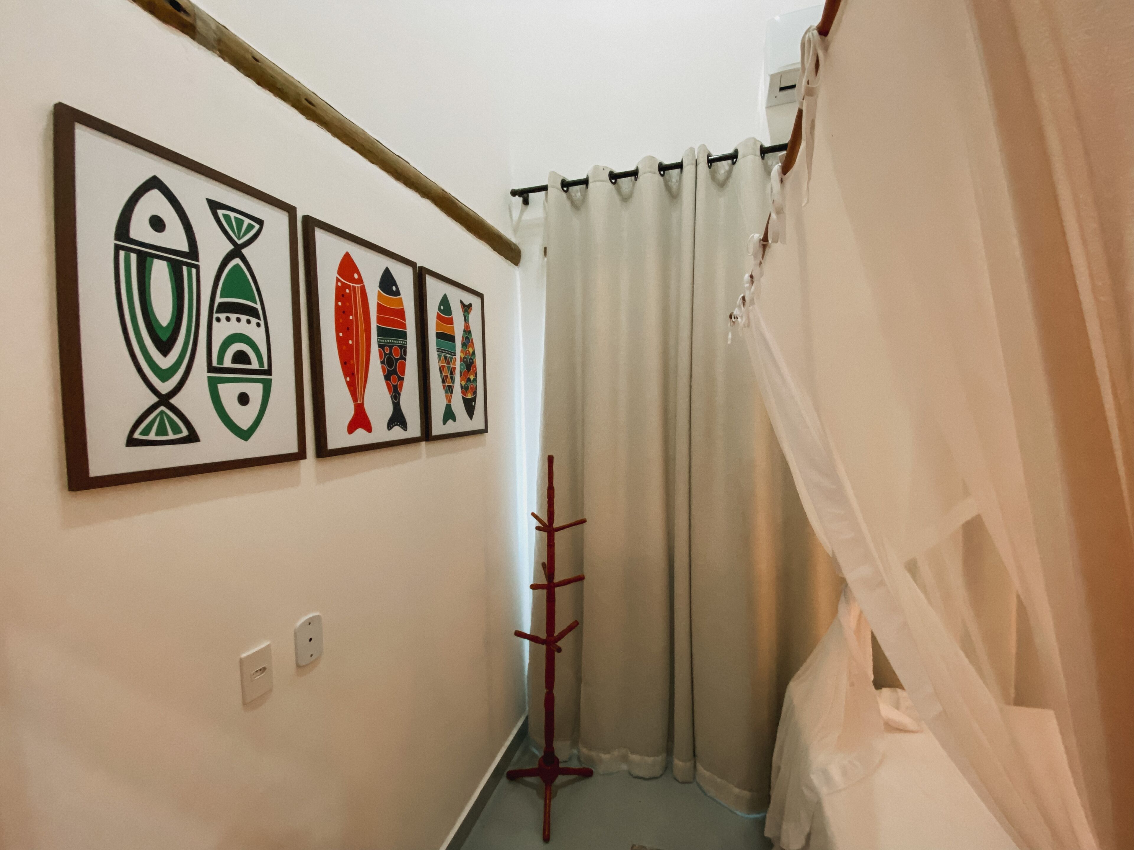Um corredor com quadros de peixes nas paredes, um porta-roupas e um cortina de chuveiro.