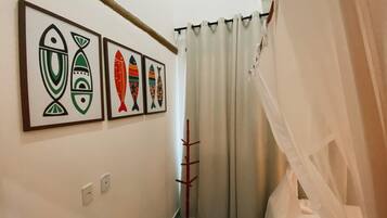 Um corredor com quadros de peixes nas paredes, um porta-roupas e um cortina de chuveiro.