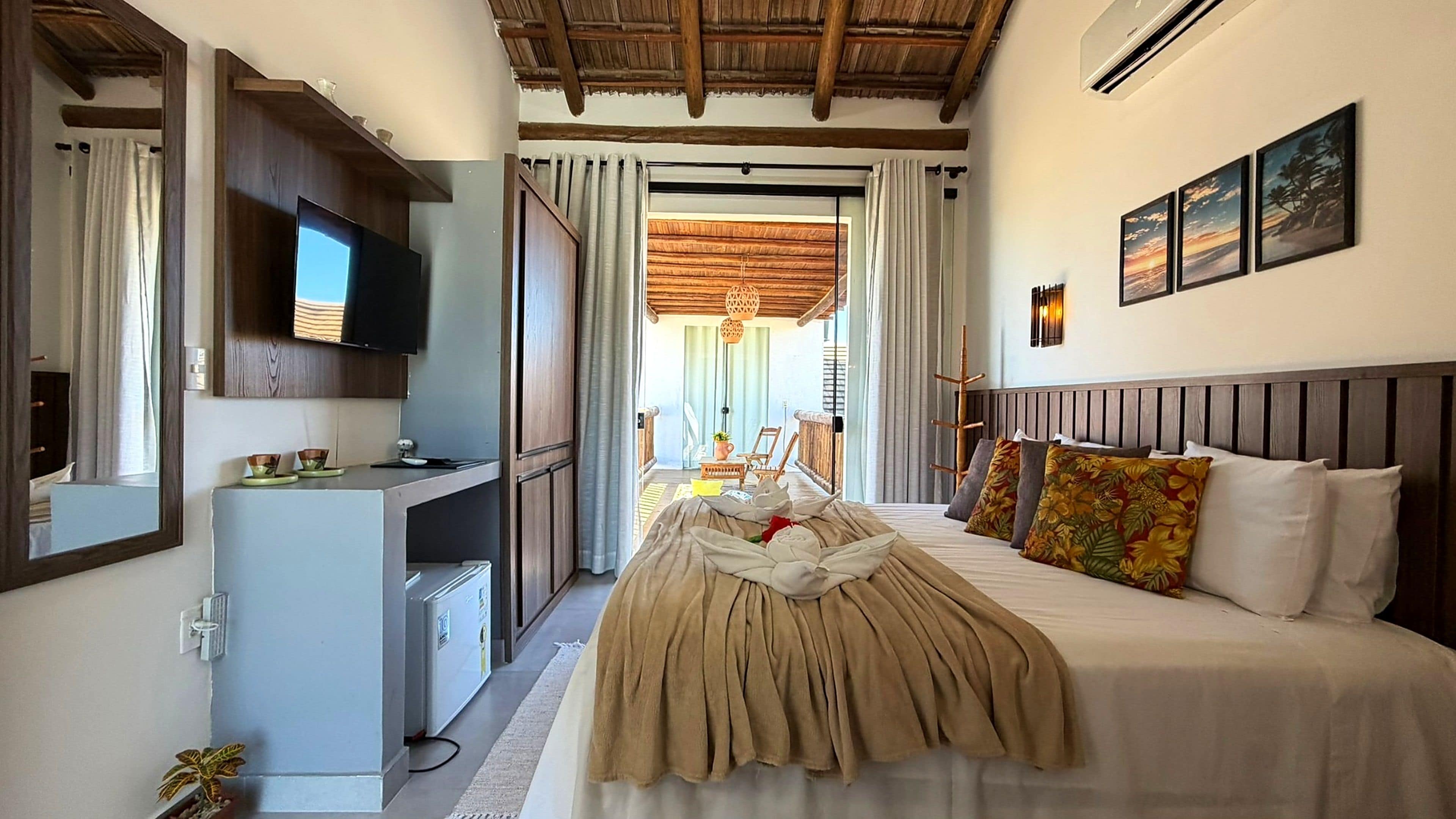 Habitación de hotel con cama, escritorio, televisor y vista al exterior.