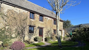 A stone building with multiple windows and a well-maintained lawn.