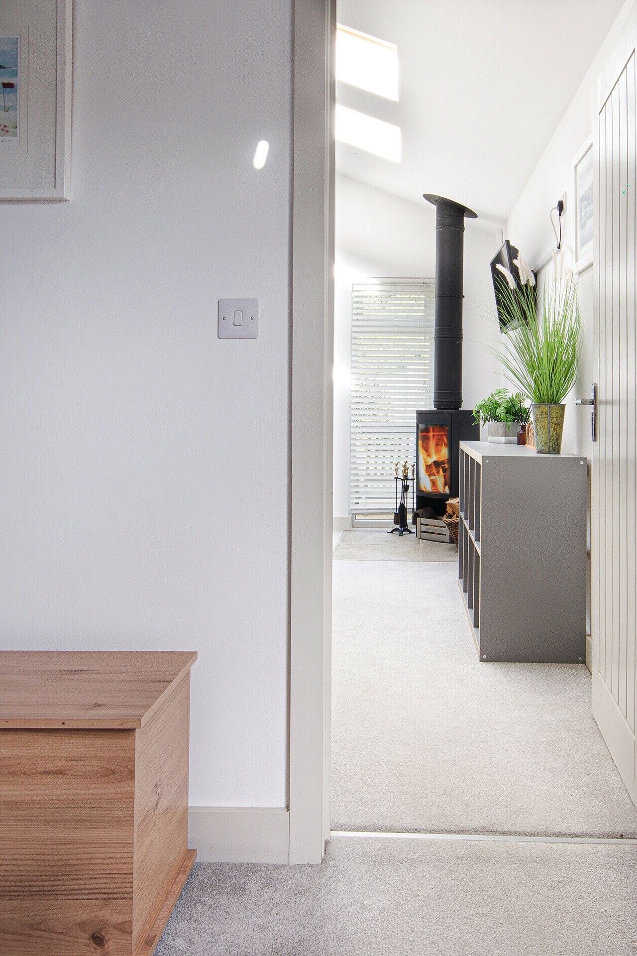 A modern living room with a fireplace, a wooden bench, and a potted plant.