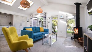 Una sala de estar moderna con un sofá azul, un sillón amarillo, una mesa de centro de vidrio y una chimenea.