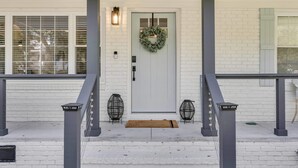 A white brick house with a front door, a wreath, and two lantern-style lights on either side. - Luxury Isle of Palms Home Steps to Beach with Pool (Isle of Palms)