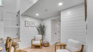 A spacious room with a dining area, two wooden chairs, a small round table, and a potted plant. - Luxury Isle of Palms Home Steps to Beach with Pool (Isle of Palms)