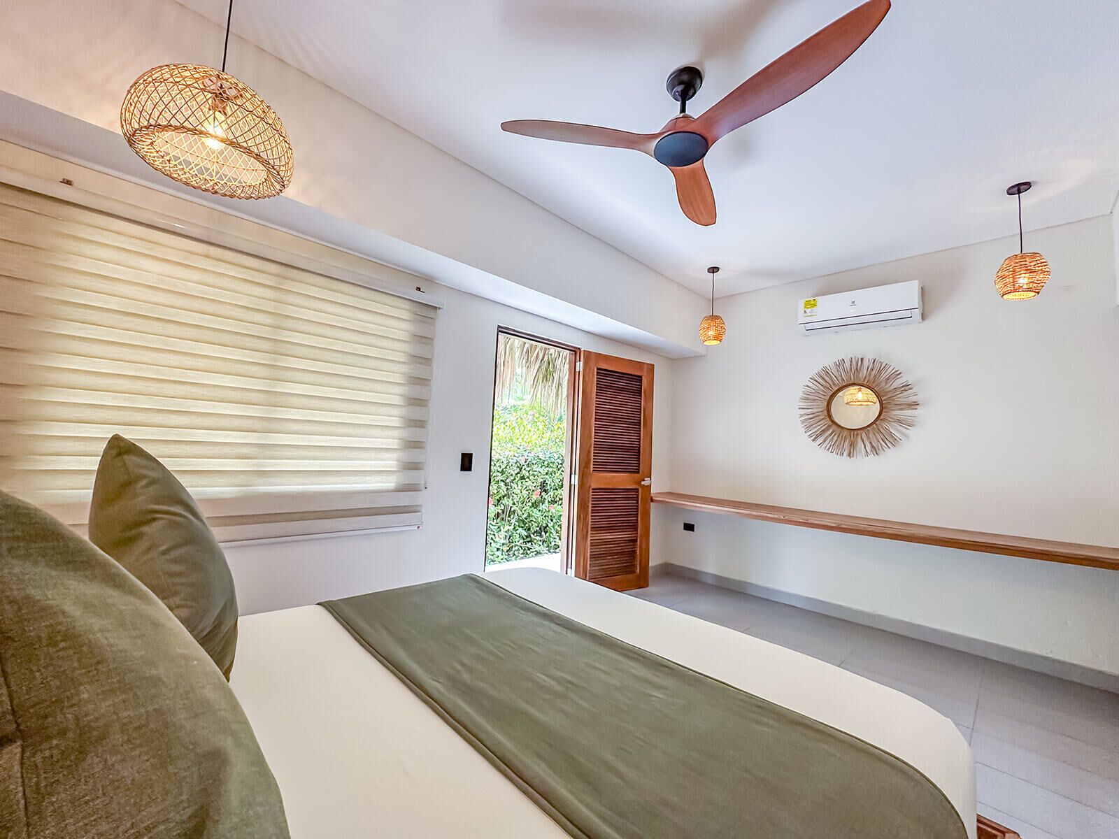 A bedroom with a bed, a ceiling fan, a window with blinds, and a door leading outside.