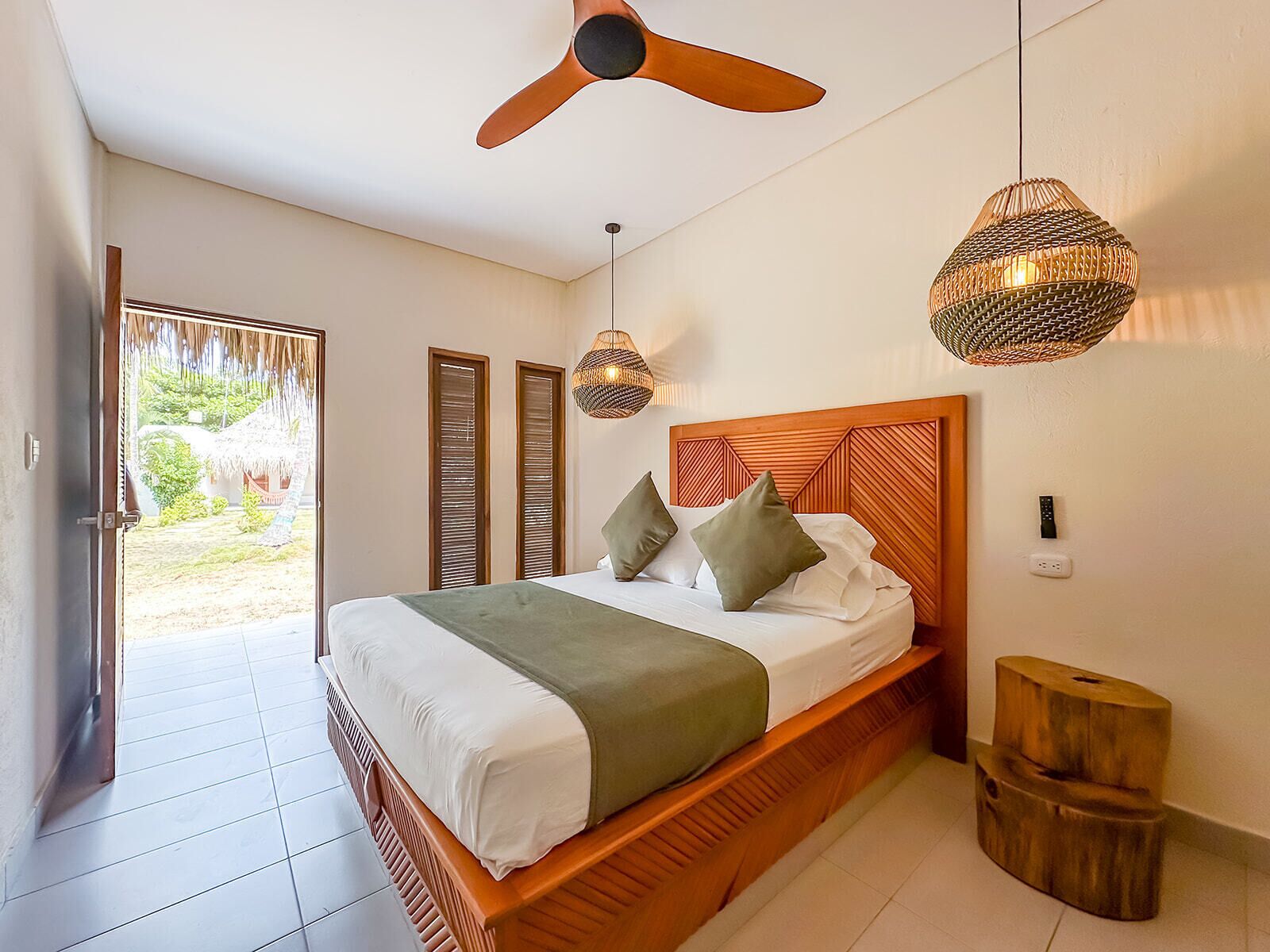 A bedroom with a wooden bed, a ceiling fan, and two woven lamps.