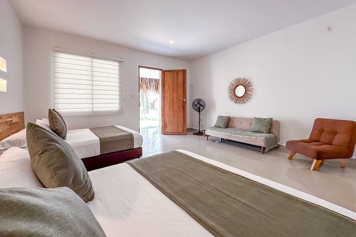 A modern bedroom with a bed, a sofa, a chair, and a fan.