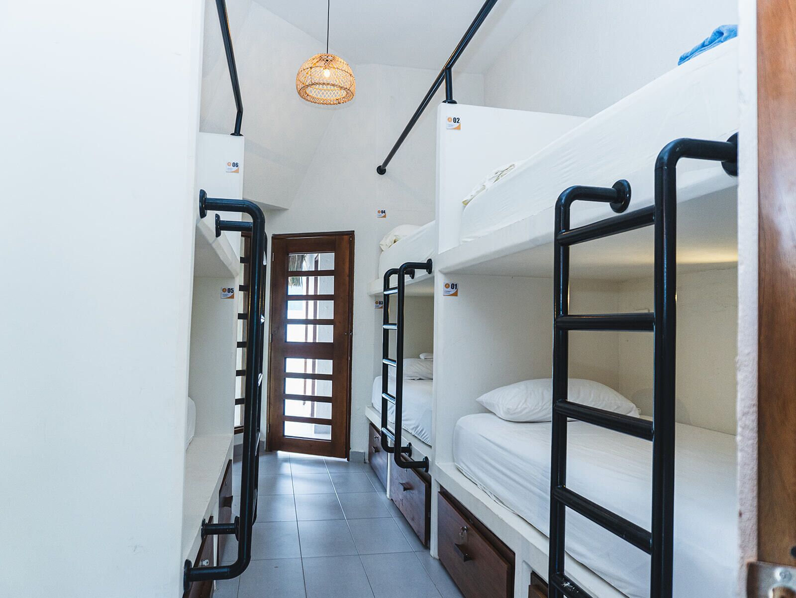 A narrow corridor with bunk beds, a wooden door, and a hanging light fixture.