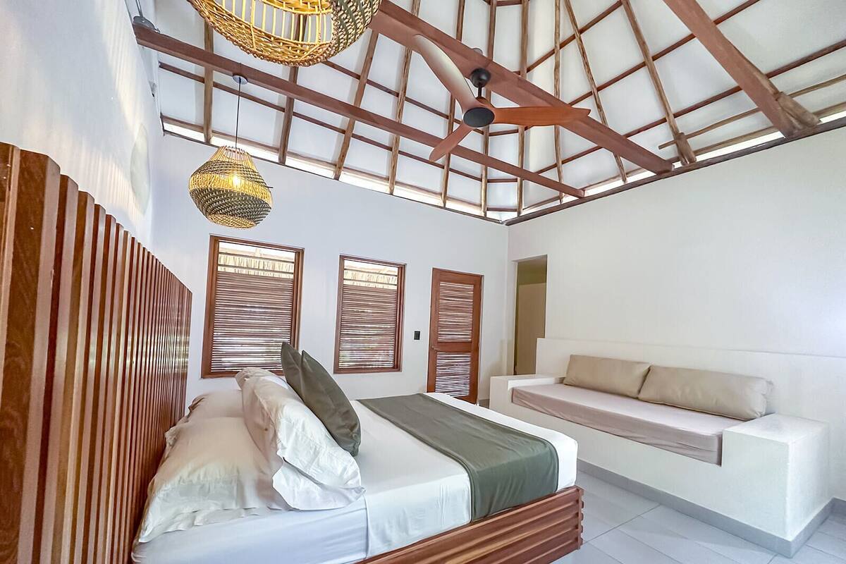 A bedroom with a bed, a bench, and a ceiling fan.