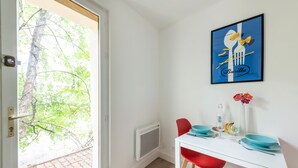 Un comedor con una mesa blanca, sillas rojas y un cartel azul y blanco en la pared.