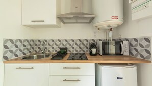Una cocina equipada con microondas, hervidor y un refrigerador pequeño.