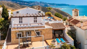 Um edifício de dois andares com piscina no terraço e vista para o mar.