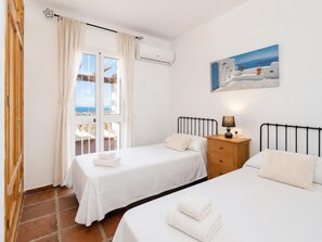 Habitación de hotel con dos camas, una mesita de noche, un cuadro y vistas a través de la ventana.