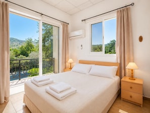 Ein Schlafzimmer mit einem Bett, zwei Nachttischen, einem Fenster und einem Balkon.