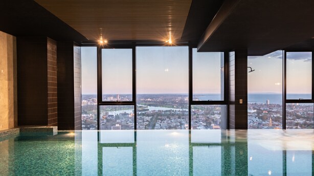 Ein großzügiger, überdachter Pool mit Blick auf die Stadt durch große Fenster.