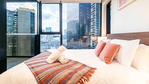 Ein modernes Hotelzimmer mit einem großen Bett, Blick auf die Stadt und einem großen Fenster.