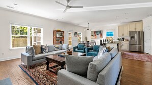 Ein geräumiges Wohnzimmer mit grauem Sofa, einem Couchtisch und einem Deckenventilator.