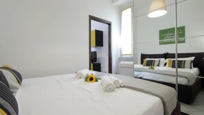 A hotel room with a large bed, a smaller bed, and a sofa bed. There is a mirror on the wall and a sign with text. - 4bnb - Ombrellari 4 (Rome)