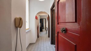 A hallway with a red door, a telephone, and a lamp. - 4bnb - Ombrellari 4 (Rome)