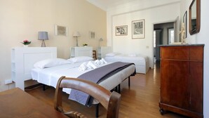Ein Hotelzimmer mit zwei Betten, einem Holzstuhl, einem Schminktisch und Bildern an den Wänden.