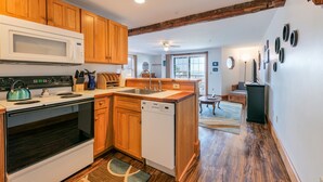 Una cocina con gabinetes de madera, microondas, estufa y lavavajillas.