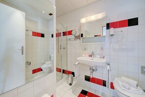 A modern bathroom with a glass shower enclosure, a white sink, and a mirror above the sink.