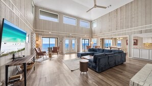A spacious living room with a large sectional sofa, a TV mounted on the wall, and a ceiling fan. - Spectacular Gulf Front 30A! Private Pool & Gulf Views, Fall Specials! (Santa Rosa Beach)