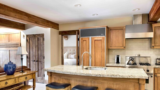 Cocina con armarios de madera, encimera de granito, pileta de acero inoxidable y estufa integrada.