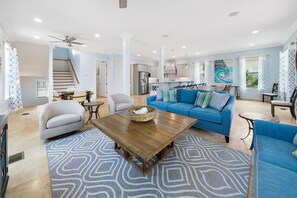 A spacious living room with a blue sofa, a wooden coffee table, and a patterned rug.