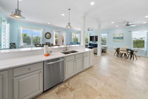 A spacious kitchen with a large island, modern appliances, and a dining area with a view. - 30A Paradise! Pool, Tiki Bar & 6-Seat Golf Cart 5-Bed Book Now for Fall! (Santa Rosa Beach)