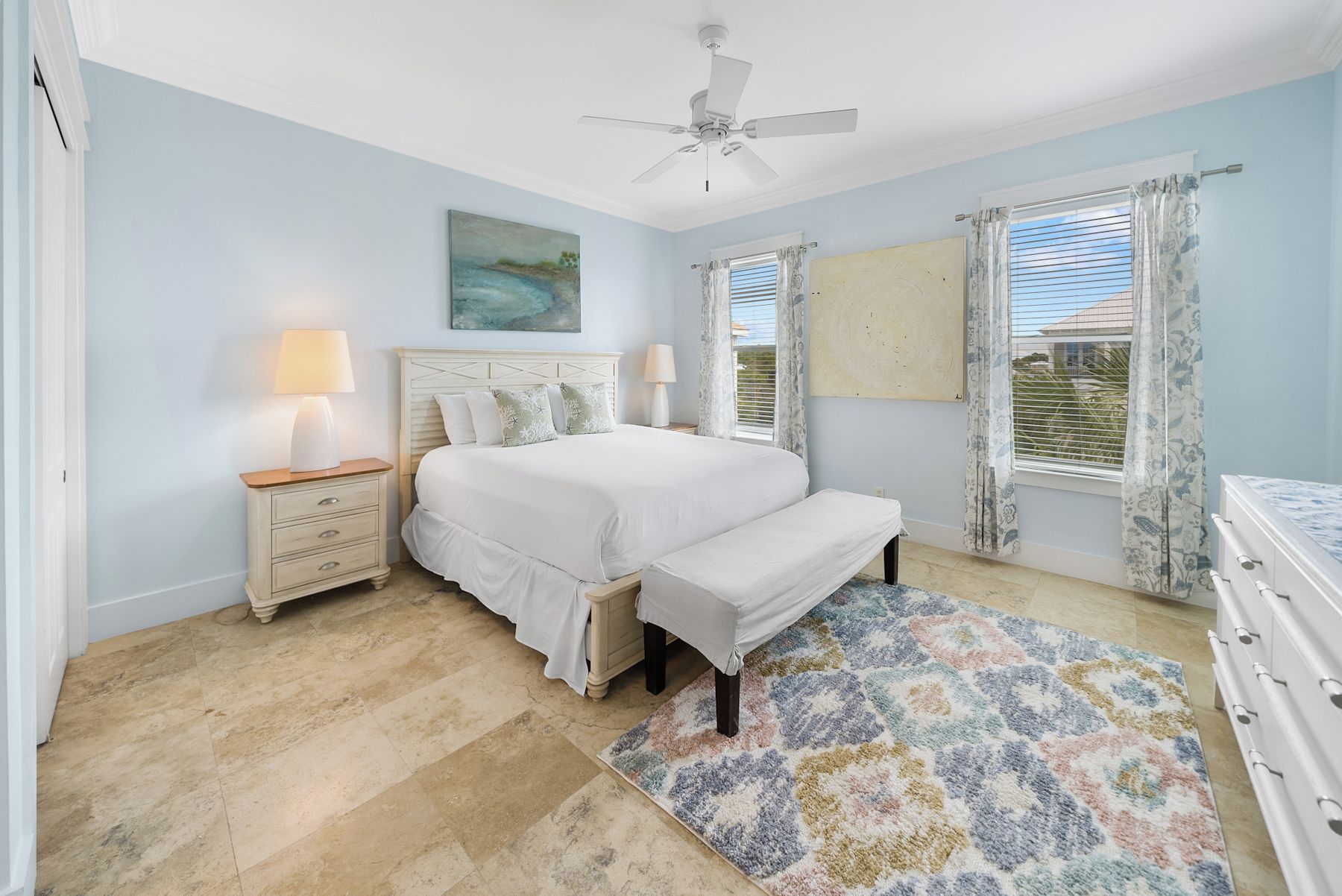 A bedroom with a bed, bedside tables, a ceiling fan, and a window with curtains.