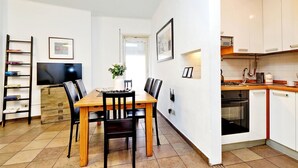 Een compacte woonruimte met een eethoek, keuken en een aan de muur bevestigde televisie.