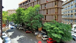 A multi-story building with a modern design, featuring a series of balconies and large windows. - 4bnb - Cavour Square Apartment (Rome)
