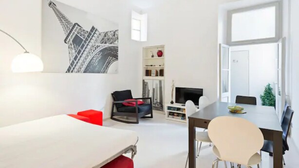 Une pièce moderne et bien éclairée, comprenant une table à manger, des chaises, un canapé et un téléviseur.