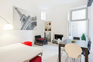 A modern, well-lit room with a dining table, chairs, a sofa, and a TV. - 4bnb - Giulio Cesare Cozy Apartment (Rome)