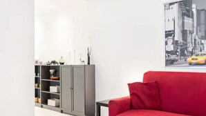 Un salon moderne avec un canapé rouge, une étagère grise et une table noire.
