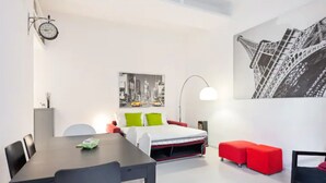 Une chambre moderne avec un lit, une table à manger et un canapé rouge.