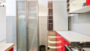 Une cuisine moderne avec des meubles blancs, une cuisinière en acier inoxydable et un garde-manger avec des portes en verre.