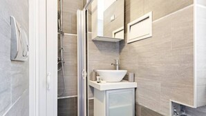 Une salle de bain moderne avec une douche à l’italienne, un lavabo blanc et un miroir au-dessus du lavabo.