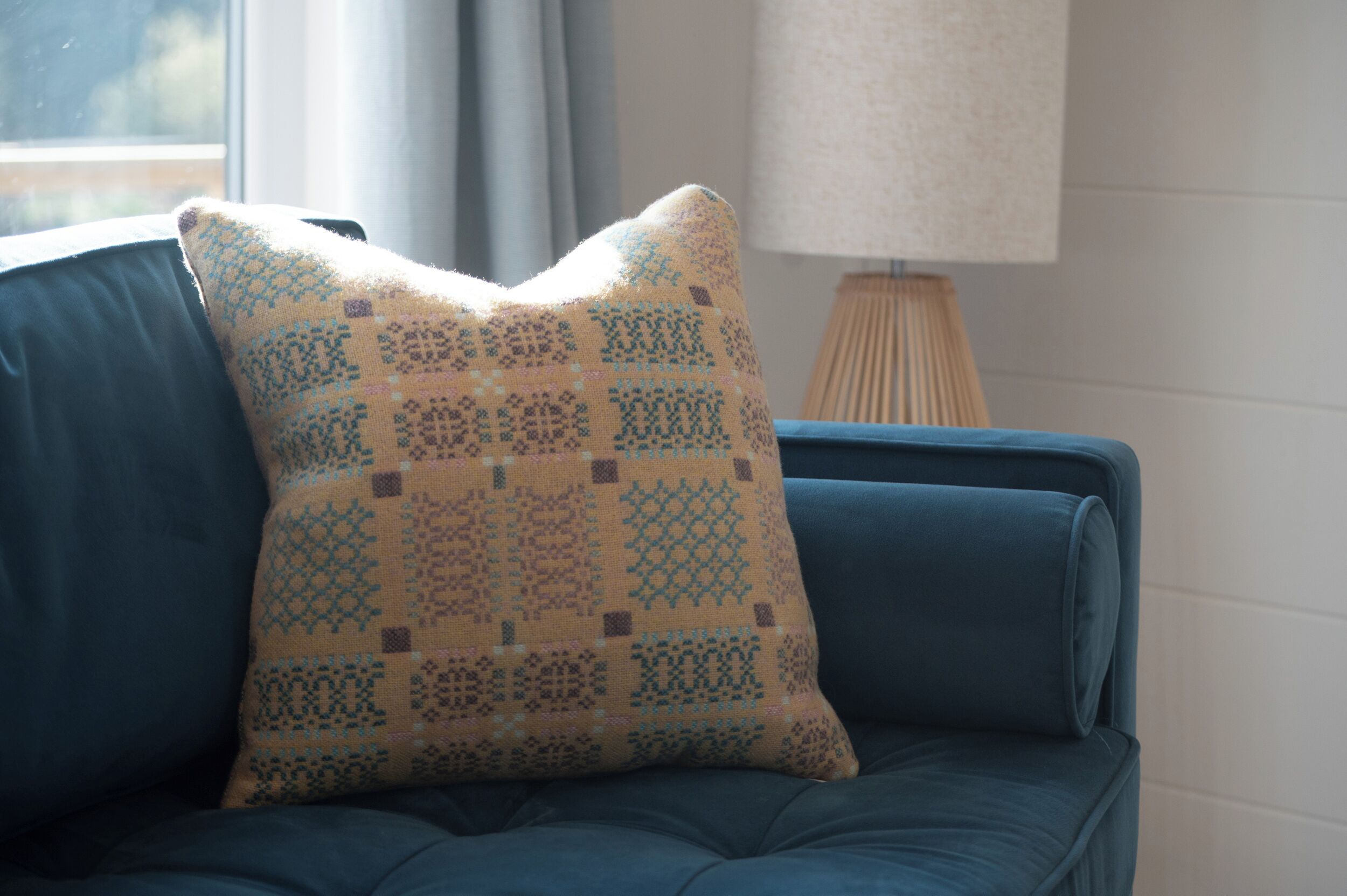 A blue sofa with a patterned cushion.