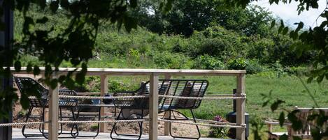 A wooden deck with metal chairs and a rope railing.