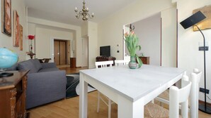 Uma sala de estar com uma mesa de jantar branca, sofá cinza e um globo em um armário de madeira.