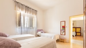 Une chambre avec deux lits, un banc et un miroir au mur.
