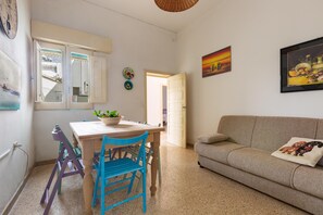 A cozy living room with a sofa and a dining area with chairs and a table. - 2743 Appartamento Ros by Barbarhouse (Porto Cesareo)